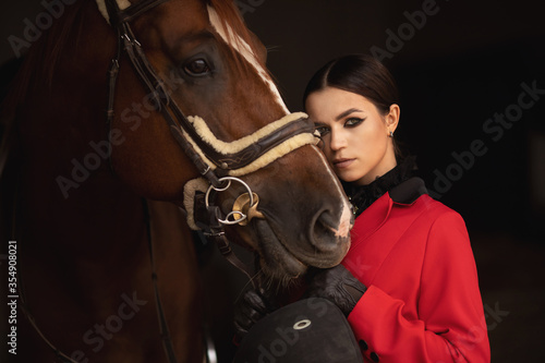 Woman jockey rider hugs brown horse with eyes closed. Concept love animals