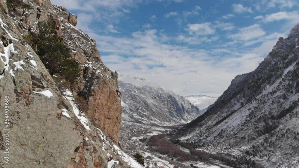 An aerial view of the span next to the rock on the mountain gorge in early spring powdered with snow. An aerial view of the span next to the rock on the mountain gorge in early spring powdered with snow.