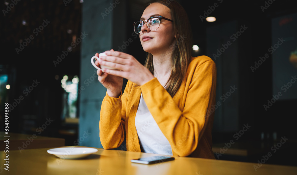 cheerful woman in fashionable apparel looking at camera and enjoying coffee break indoors cheerful woman in fashionable apparel looking at camera and enjoying coffee break indoors