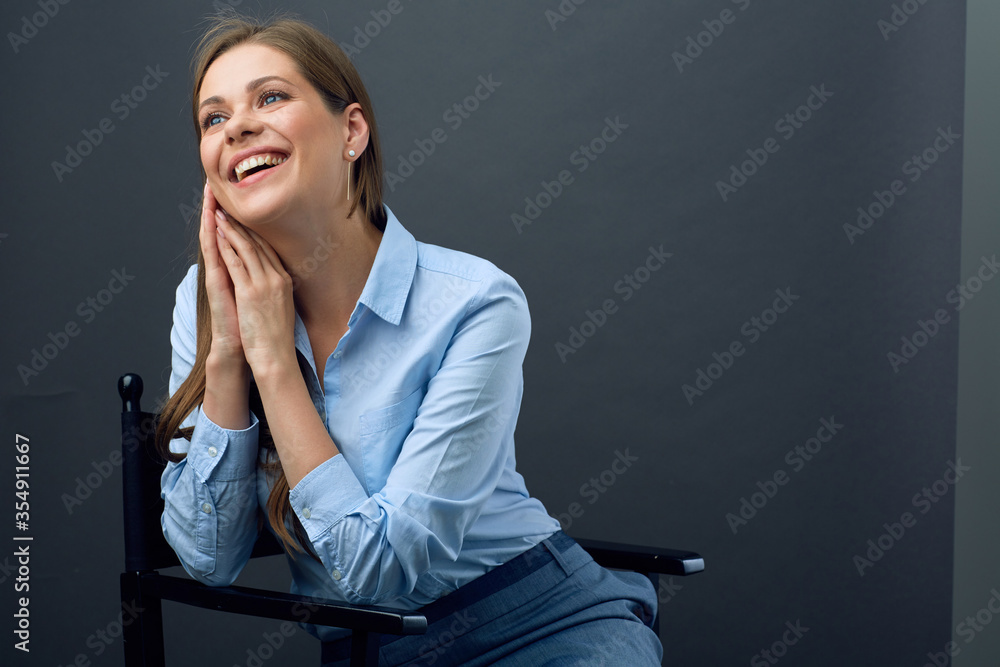 Happy woman dressed blue shirt looking away sitting on black chair. Happy woman dressed blue shirt looking away sitting on black chair.