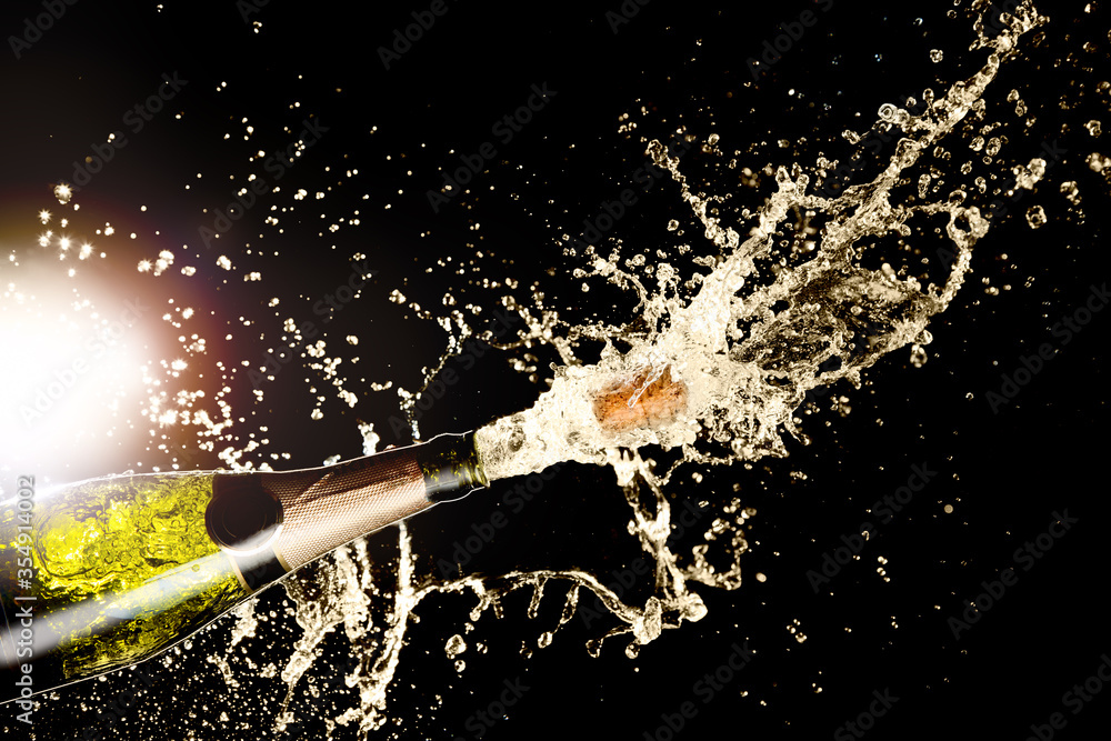 Celebration theme with splashing champagne on black background with light flare. Christmas or New Year, Valentines day background.