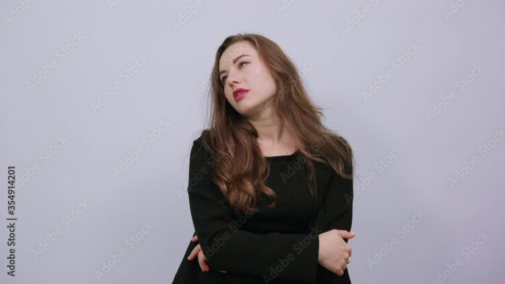 Young Attractive Woman Brunette In In A Black T-Shirt, Sweater On White Background, Focused Female Holds Fingers To Her Head And Thinks. The Concept Of Smart People, Intellectuals. Young Attractive Woman Brunette In In A Black T-Shirt, Sweater On White Background, Focused Female Holds Fingers To Her Head And Thinks. The Concept Of Smart People, Intellectuals.