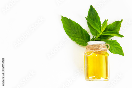 mint oil in a decorative bottle and green mint leaves