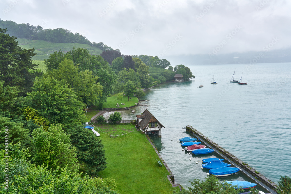 Obraz premium Landscape of Thun Lake on a rainy and foggy day. Taken in Spiez, Swiss Alps, Switzerland