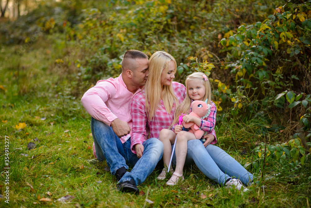 Father mother and daughter are sitting on the grass. Father mother and daughter are sitting on the grass.
