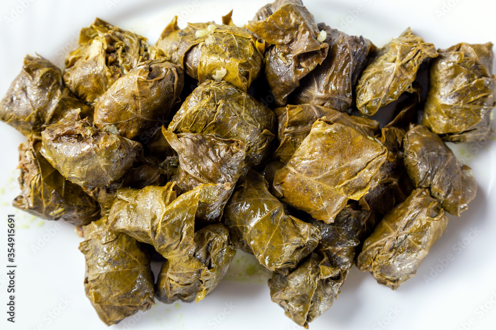 Dolma stuffed meat in grape leaves on white plate close up. Top view Dolma stuffed meat in grape leaves on white plate close up. Top view