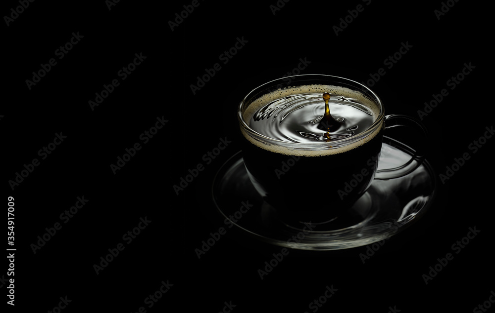 a Cup of coffee with a falling drop on a black background a Cup of coffee with a falling drop on a black background