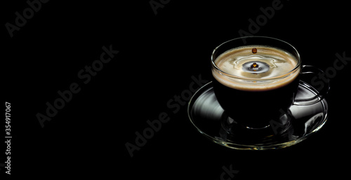 a Cup of coffee with a falling drop on a black background