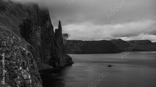 Dramatic B&W 4k timelapse video of Trollkonufingur -Witch Finger- Fjord under the clouds on Vagar island, Faroe Islands
 photo
