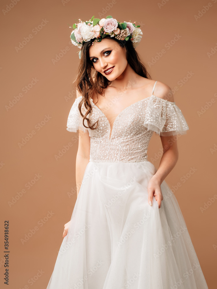 Boho wedding style. Beautiful bride in a white wedding dress with sleeves and floral garland on beige background. Boho wedding style. Beautiful bride in a white wedding dress with sleeves and floral garland on beige background.