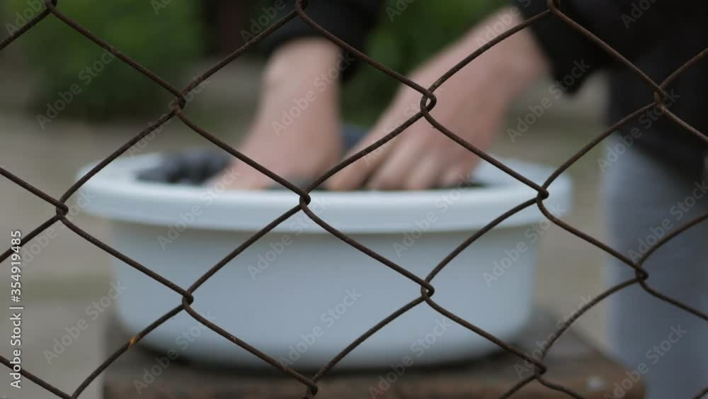 The view through the bars, female hands, wash clothes in a basin with detergent. The view through the bars, female hands, wash clothes in a basin with detergent.