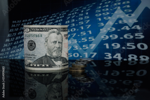 on a glass table in a twisted form is the American dollar against a background of economic graphs and numbers.