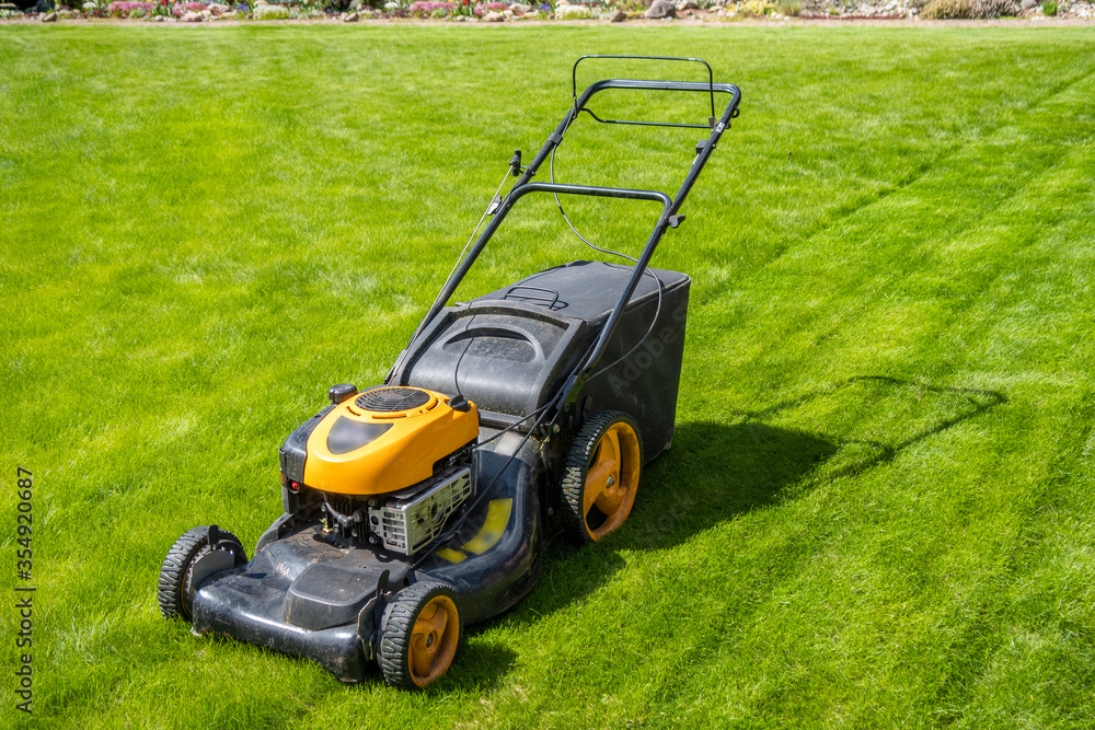 Lawn mower on fresh green lawn, freshly cut grass on summer sunny day Lawn mower on fresh green lawn, freshly cut grass on summer sunny day