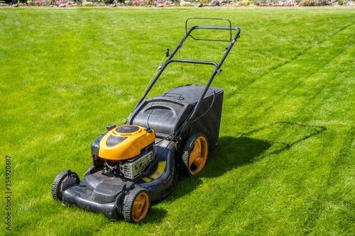 Lawn mower on fresh green lawn, freshly cut grass on summer sunny day