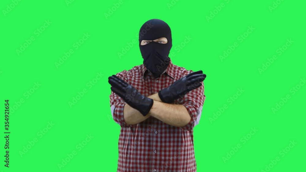 A man in a balaclava in a plaid shirt shows his hands with his feet. A man in a balaclava in a plaid shirt shows his hands with his feet.