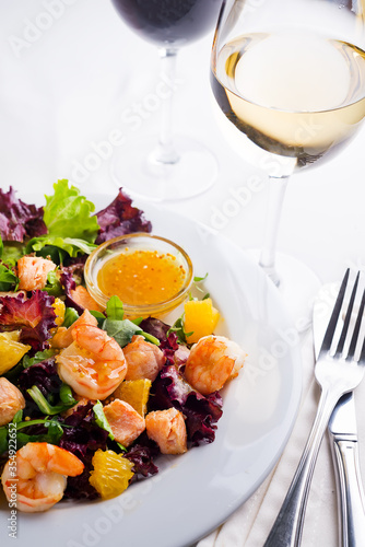 Healthy salad with prawns, lettuce, oranges and mango served on a plate with orange mustard sauce photo