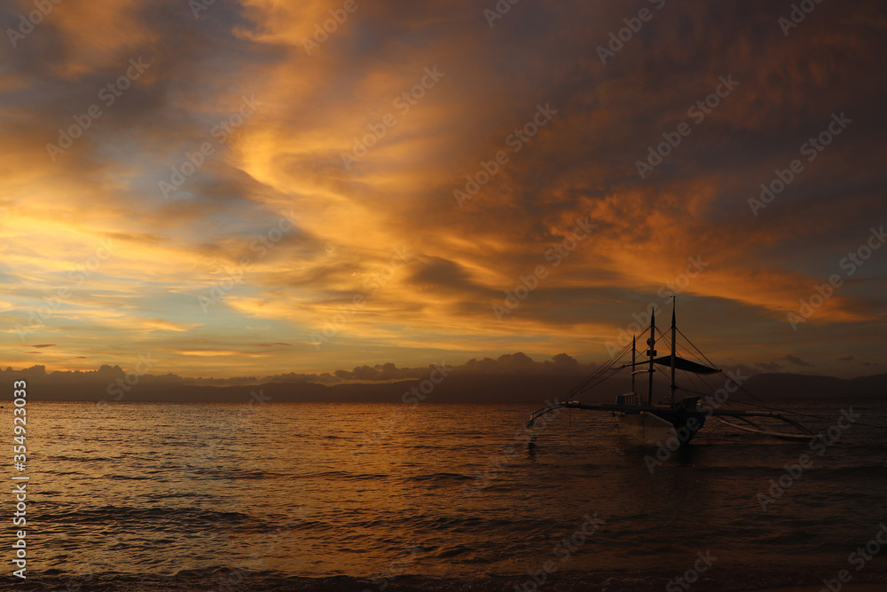 Pleasure boat against the backdrop of a cloudy golden sunset at sea in the Philippines.