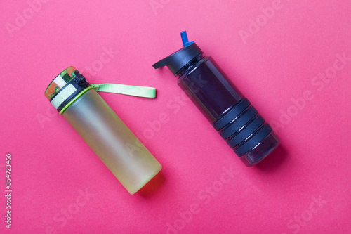black and green sport plastic bottles lying on red colored paper background