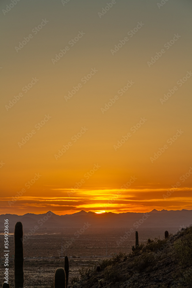 The sunsetting over distant mountains with an orange glow in the sky