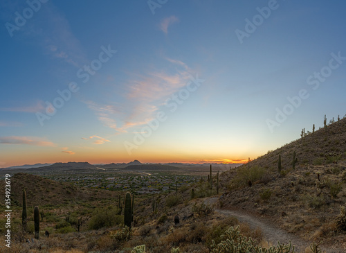 A desert trail on a mountain leading to a sunset over a valley in Phoenix