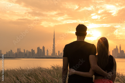 Canvas Print Two lovers on holiday looking at the city view during a beautiful orange sunset sky background