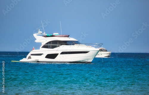 A luxury yacht sailing on the sea with clear blue sky and horizon visible in the background 