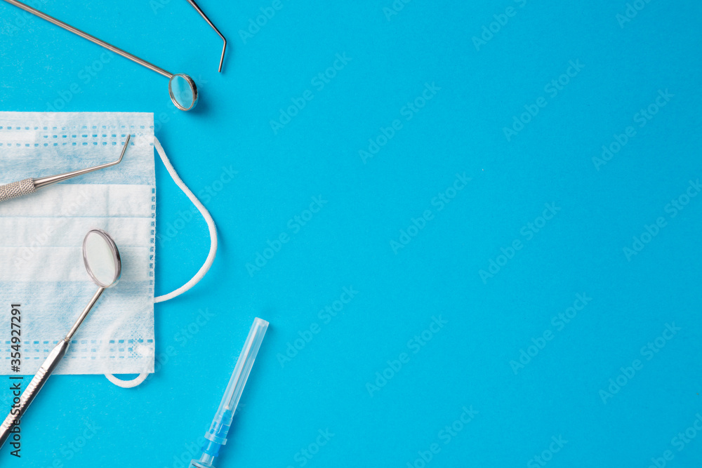 Dental hygiene and health concept. Dentist tools or instruments dental explorer, dental mirrors, syringe and procedure face mask on light blue background. Free space. Dental hygiene and health concept. Dentist tools or instruments dental explorer, dental mirrors, syringe and procedure face mask on light blue background. Free space.