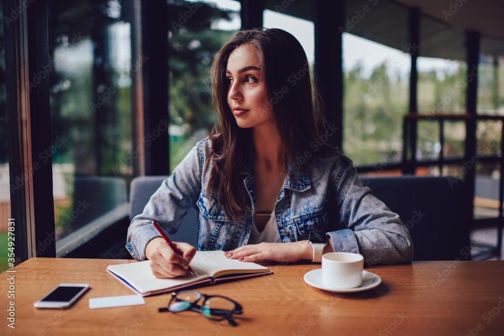 Portrait of attractive student looking at camera while writing down text information in notepad. Portrait of attractive student looking at camera while writing down text information in notepad.