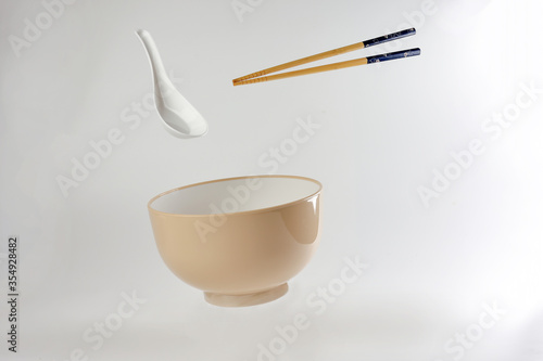Empty oriental Japanese Chinese soup bowl spoon chopstick elevated flying in air off white