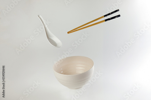 Empty oriental Japanese Chinese soup bowl spoon chopstick elevated flying in air off white