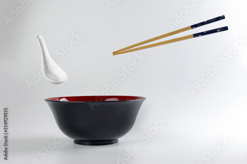 Empty oriental Japanese Chinese soup bowl spoon chopstick elevated flying in air red black white
