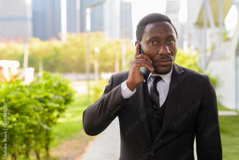 Handsome bearded African businessman talking on the phone at the park Handsome bearded African businessman talking on the phone at the park
