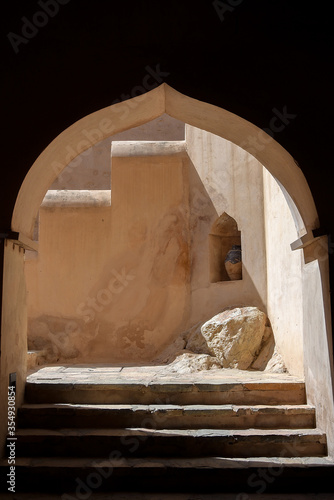 Ogee archway into an ancient fortress built into the side of a mountain with old steps heading into it