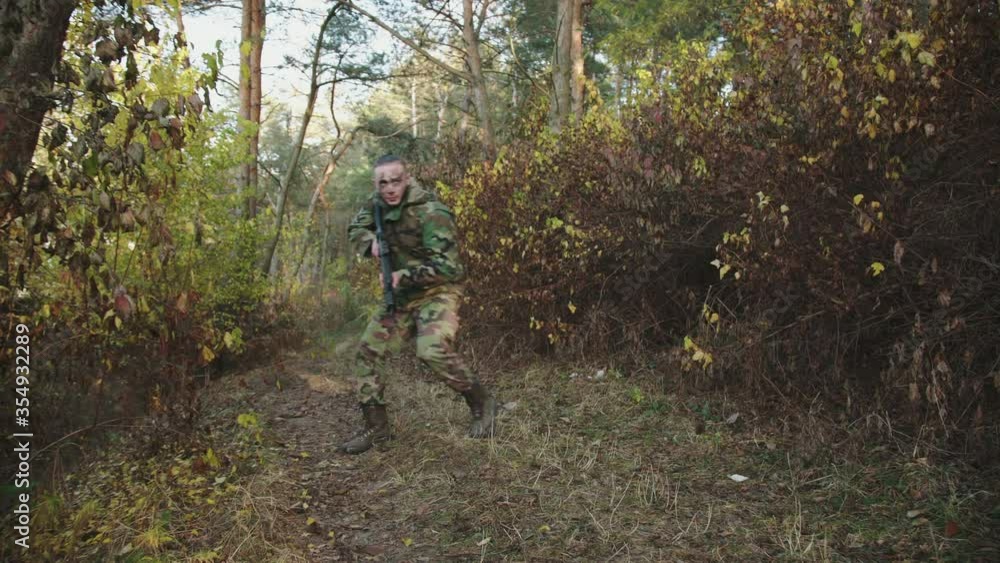 The soldier aims in different directions on object with a rifle sight at forest The soldier aims in different directions on object with a rifle sight at forest