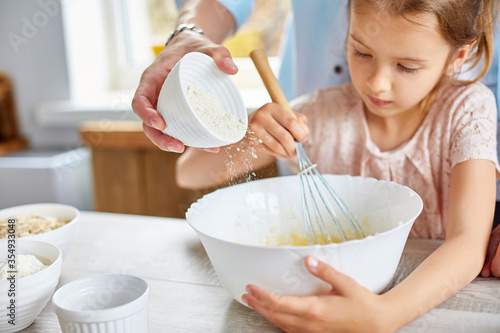 Father and daughter preparing dough together in kitchen