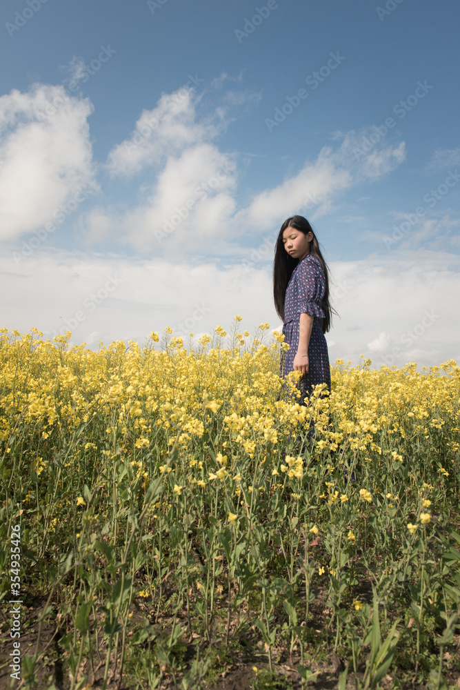 Teenage girl in blue dress standing in wild flower field Teenage girl in blue dress standing in wild flower field