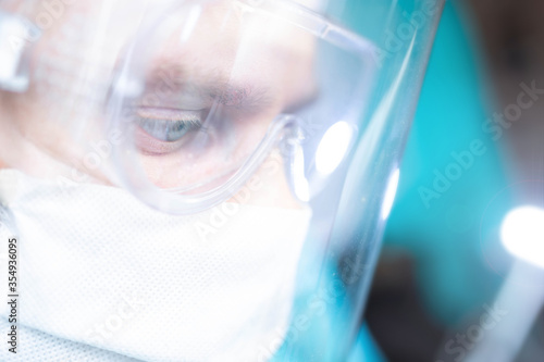 surgeon with glasses and a protective shield and mask. Young specialist works in the operating room