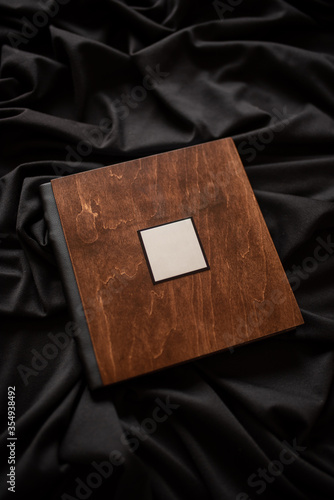Wooden book with a nameplate on a black fabric background.