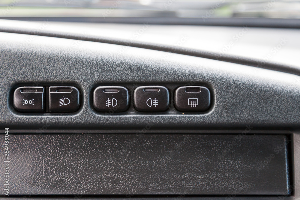 A row of buttons for controlling the light and heating the rear window in black with white symbols of an old Russian car on a gray plastic panel close-up. A row of buttons for controlling the light and heating the rear window in black with white symbols of an old Russian car on a gray plastic panel close-up.