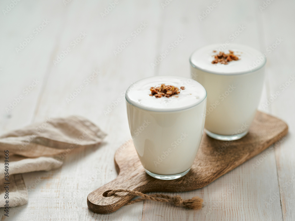 Kefir, buttermilk or yogurt with granola. Yogurt in glass on white wooden background. Probiotic cold fermented dairy drink. Gut health, fermented products, healthy gut flora concept. Copy space Kefir, buttermilk or yogurt with granola. Yogurt in glass on white wooden background. Probiotic cold fermented dairy drink. Gut health, fermented products, healthy gut flora concept. Copy space