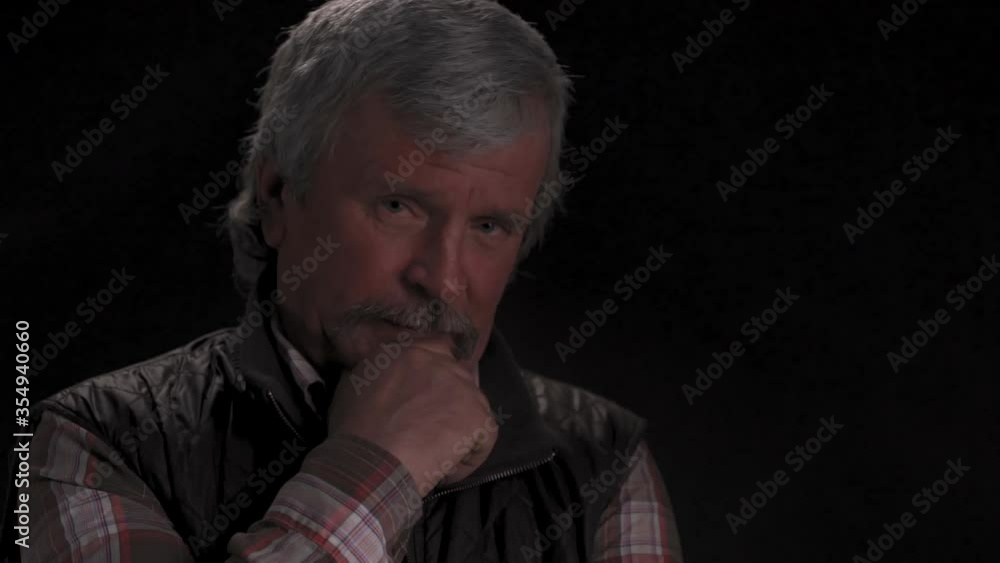 Senior old man loses his beard looking at the camera standing in a studio in a semi lit light room isolated on a black background. Prores 422. Senior old man loses his beard looking at the camera standing in a studio in a semi lit light room isolated on a black background. Prores 422.