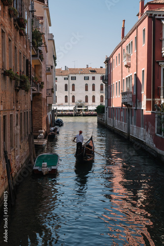 Gondolier drives a gondola with tourists on a canal in Venice, Italy.