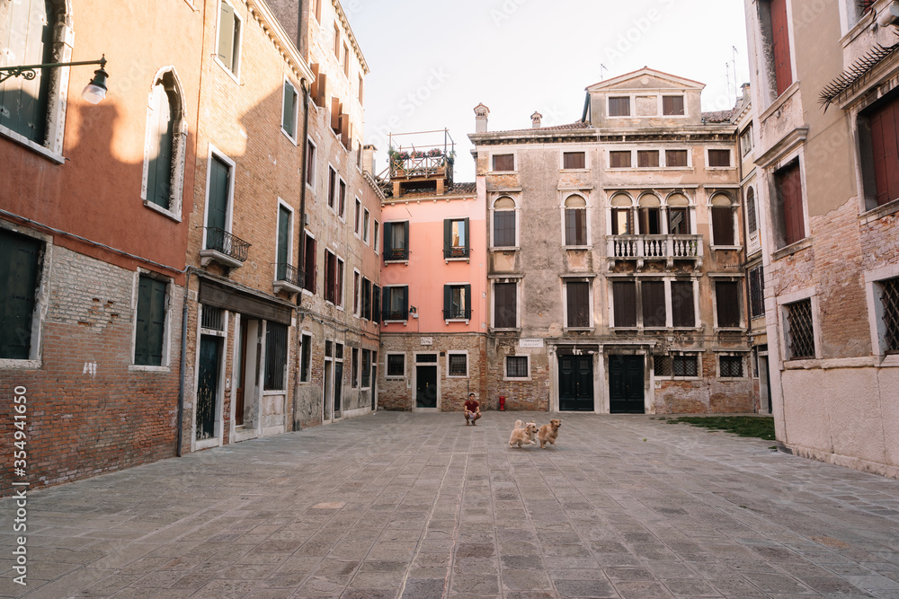 One man is walking with two dogs at the yard of Venice, Italy.