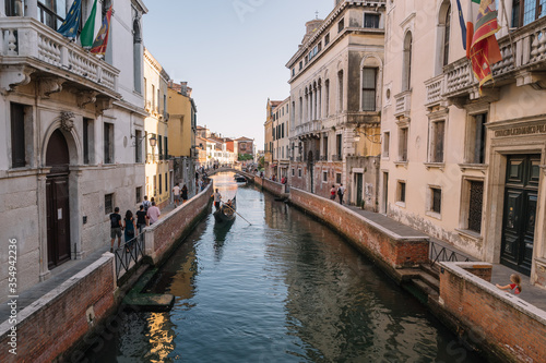 Tourists are walking by the canal of Venice, Italy.