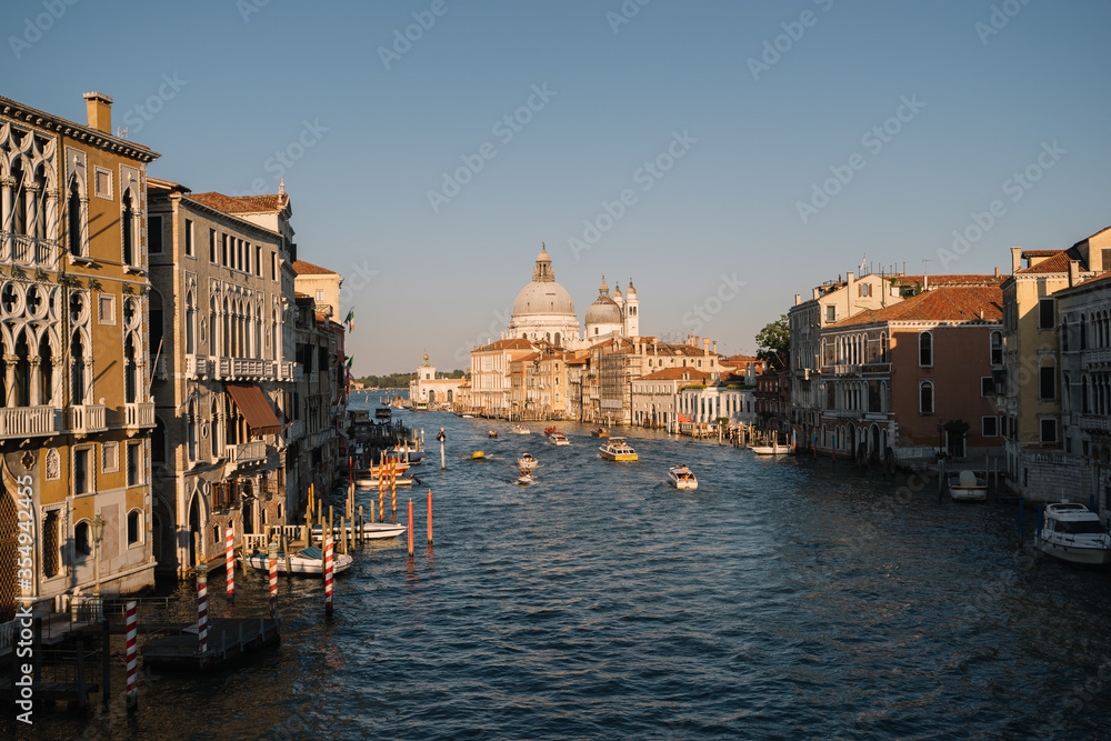 Boats are driving on the Grand Canal at sunset in Venice, Italy.