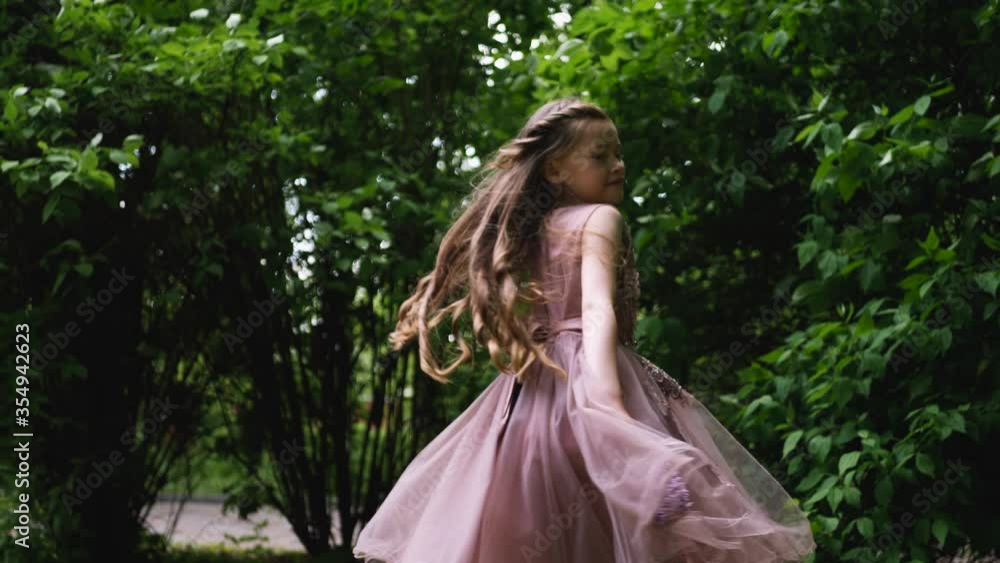 girl in a purple puffy dress swirls near green bushes girl in a purple puffy dress swirls near green bushes