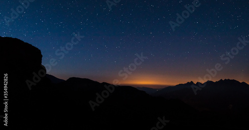 Early morning panorama viewed from Grossglockner mountain pass, with visible multitude of stars on the sky above the mountains. Sun is slowly starting to rise and glow is visble. photo