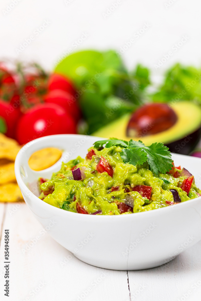 Bowl of Guacamole next to Fresh Ingredients on a Table with Tortilla Chips. Selective focus. Bowl of Guacamole next to Fresh Ingredients on a Table with Tortilla Chips. Selective focus.