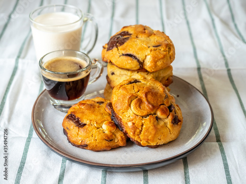 Chunky chewy chocolate chip soft cookies with cups of coffee and milk for breakfast, selective focus on cookies