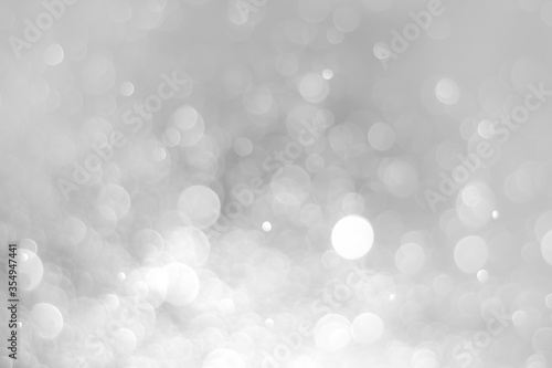 White glitter vintage lights background. White bokeh on black background.